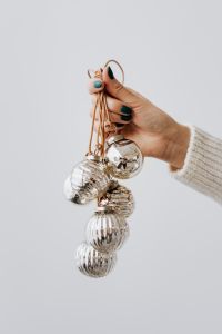 Hand Holding Christmas Tree Baubles on a White Background