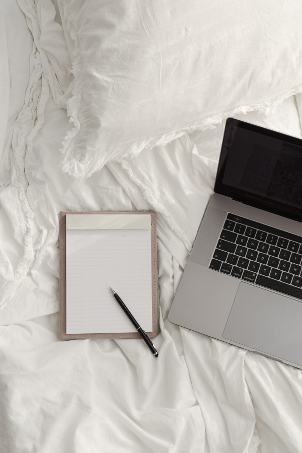 Working with a laptop in bed - white cotton bedding - blank notebook ...