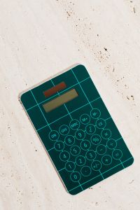 Kaboompics - Teal Calculator on a Neutral Stone Surface for Homework, Budgeting and Math Study