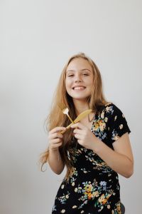 Kaboompics - Smiling Young Woman Holding Wooden Salad Servers against a White Background