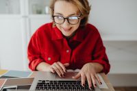 Kaboompics - Woman Typing on Laptop beside Notebook, Smartphone and Color Swatches at Home Office