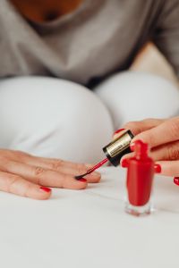 Kaboompics - Woman Painting Her Nails Red at Home, Vertical Beauty Routine Close-Up