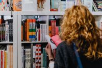 Kaboompics - Woman looking for a book in store