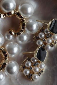 Kaboompics - Macro Jewelry Photo of Pearls and Black Stone Earrings on Soft Fabric
