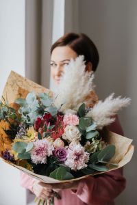 Kaboompics - Woman Peeking from Behind a Paper-Wrapped Flower Bouquet