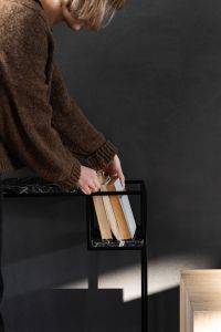 Kaboompics - Woman Arranging Books on a Black Marble Console in a Dark Modern Interior