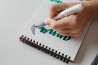 Kaboompics - Hand Shading a Logo Sketch with Gray Marker in a Spiral Notebook, Branding Design