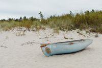 Kaboompics - Weathered Blue Fishing Boat Resting on Sandy Beach by Coastal Dune Grass