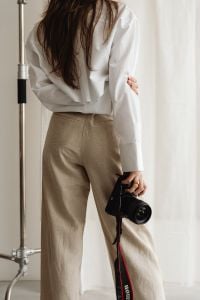 Kaboompics - Faceless Young Female Photographer Holding DSLR in Beige Trousers