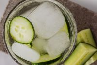 Kaboompics - Overhead Macro of Cucumber Slices and Ice in Clear Detox Water with Fresh Cucumber Spears, Textured Stone Background