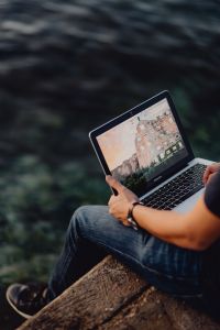 A man using a Macbook laptop at the seaside