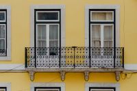 Kaboompics - Yellow Lisbon Facade with Ornate Black Iron Balcony and Tall Windows