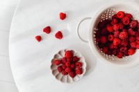 Kaboompics - Overhead Colander And Flower Dish Filled With Raspberries