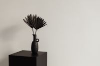 Kaboompics - Single Black Palm Fan in a Ceramic Vase on a Pedestal, Bright Neutral Copy Space