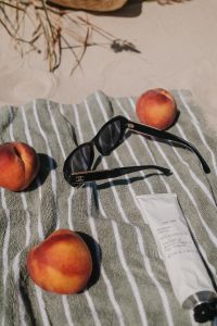 Kaboompics - Peaches, Sunglasses and Sunscreen on a Beach Towel