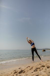 Kaboompics - Woman Stretching on the Beach by the Sea