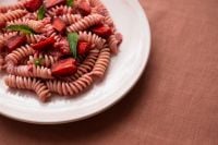 Kaboompics - Pink Fusilli With Strawberries on a Coral Linen Table