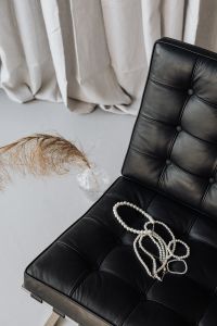 Kaboompics - Pearl Necklaces Styled on a Black Barcelona Chair with Dried Palm