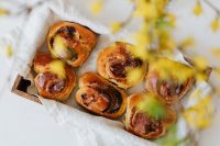 Kaboompics - Wooden Tray of Cinnamon Rolls with Forsythia Bokeh for Spring Dessert Backgrounds