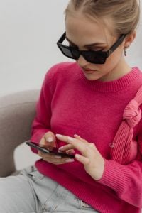 Kaboompics - Woman in Pink Sweater and Black Sunglasses Using a Phone
