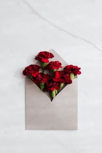 Kaboompics - Open Envelope with Red Carnations on White Marble Background