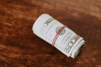 Kaboompics - Rolled US Dollar Banknotes Tied with Red String on a Wooden Table