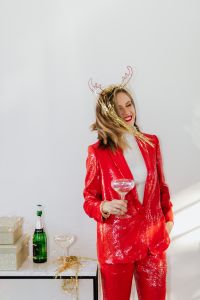 Kaboompics - Playful Champagne Party Portrait in Red Suit beside a Gift Table