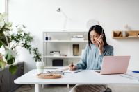 Kaboompics - Asian Woman on a Phone Call While Writing at an Office Desk