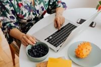 Kaboompics - Woman Working at a Laptop with Blueberries and Kiwano Fruit