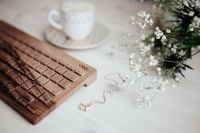 Kaboompics - Wooden Keyboard and Cappuccino with White Flowers and Necklace