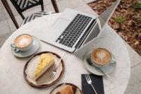 Kaboompics - Laptop, Coffee Cups and Cake on a Cafe Table