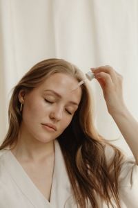 Kaboompics - Woman Applying Facial Serum with a Dropper in a White Robe