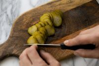 Kaboompics - Hands Cutting Pickles into Thin Slices on Wooden Board, Kitchen Food Prep