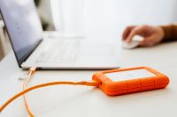 Kaboompics - Man works on a computer at his desk, mobile phone, portable hard drive