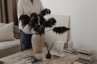 Kaboompics - Woman Sitting on the Floor Beside Black Dried Pampas Grass and Books