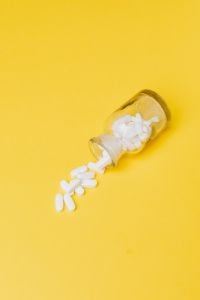 White Pills in Yellow Bottle – Medication and Healthcare Still Life