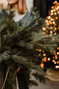 The woman is holding pine branches in her hands