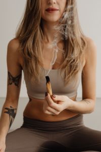 Kaboompics - Woman Holding a Smoking Palo Santo Stick While Seated Cross-Legged