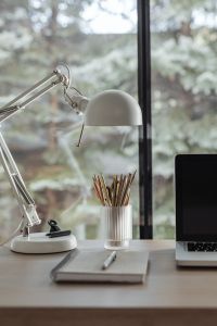 Kaboompics - Vertical Home Office Still Life with Desk Lamp, Pencils and Laptop against Greenery