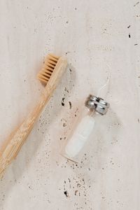 Kaboompics - Bamboo Toothbrush with Glass Dental Floss Dispenser, Minimal Reusable Oral Care on Travertine