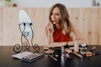 Kaboompics - Woman Applying Lipstick at a Vanity with Makeup Palette and Brushes in Foreground