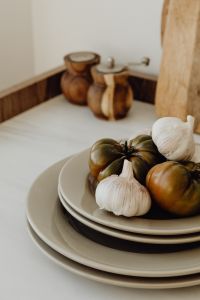 Kaboompics - Tomatoes and Garlic on Stacked Ceramic Plates with Wooden Mills in Soft Focus