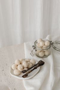 Kaboompics - Hand Serving a Coconut Truffle with a Spoon over an Open Jar, Bright Homemade Snack Lifestyle