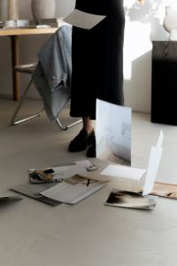 Kaboompics - Designer in Black Dress Reviewing Architectural Prints in a Bright Studio