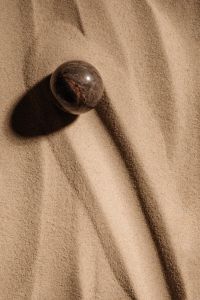 Kaboompics - Dark Round Stone Casting a Shadow on Sand