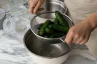 Kaboompics - Fresh Cucumbers in a Metal Colander over a Bowl, Overhead Kitchen Scene