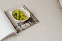 Kaboompics - Sunlit Grapes and Open Magazine Styled on a Beige Couch