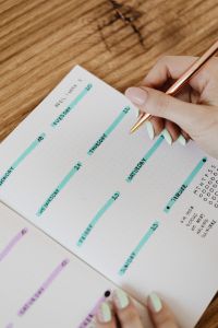 Kaboompics - Overhead View of Hand Completing a Weekly Planner