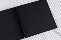 Kaboompics - Open Black Notebook on Ribbed Marble Surface, Clean Stationery Flat Lay