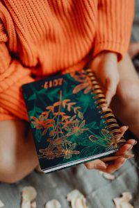 Kaboompics - A woman in an orange sweater holds the 2019 calendar in her hands